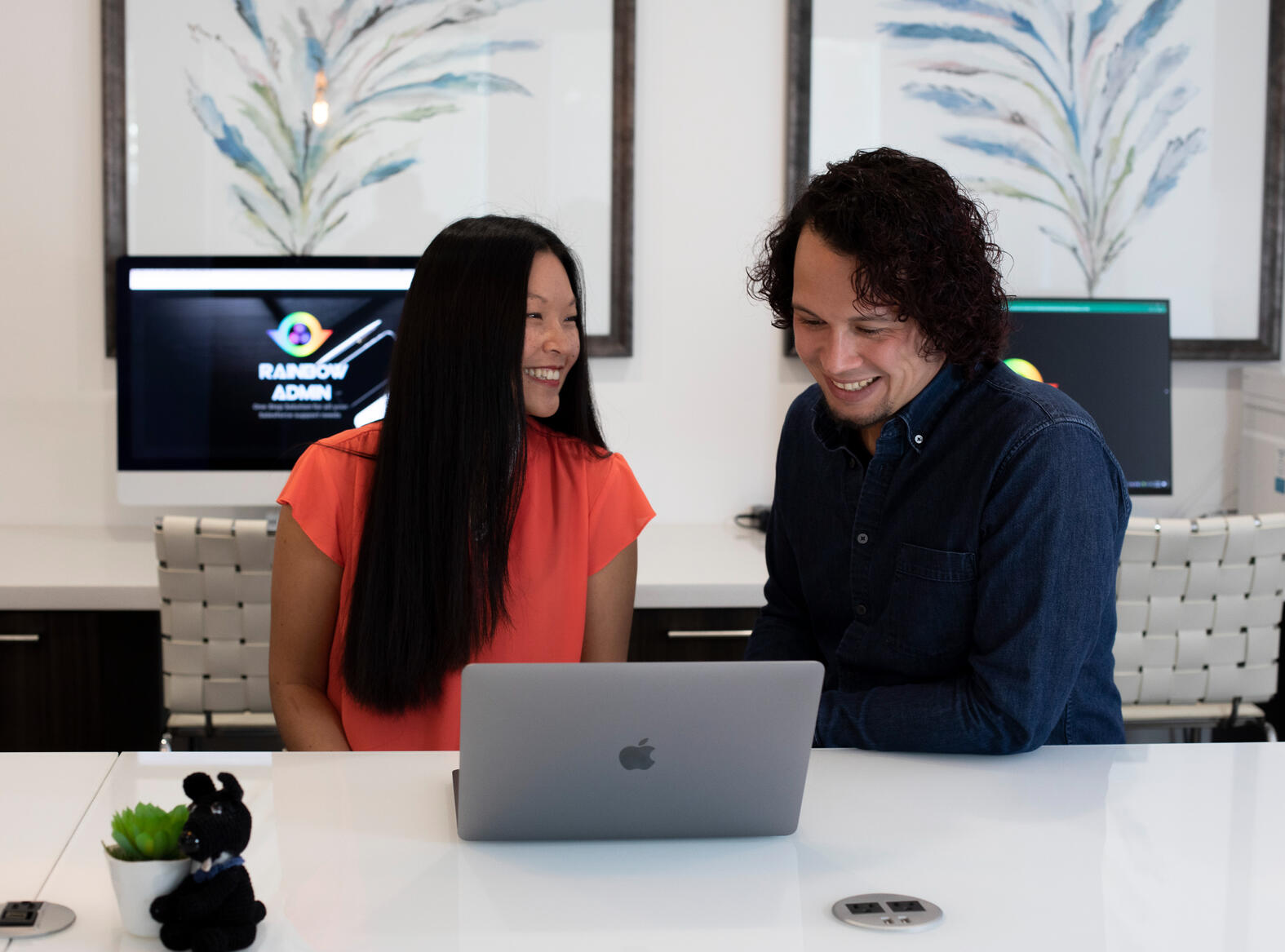 Who We Are Two people at a desk looking at a computer in an office setting